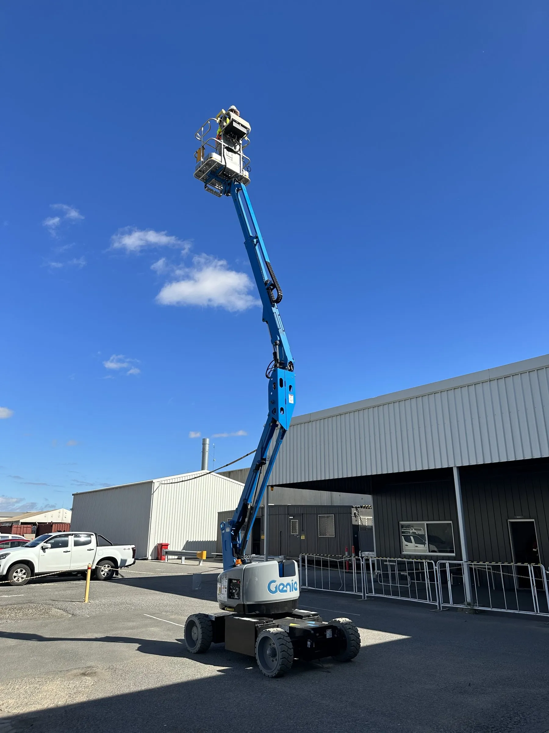 Boom lift raised beside a warehouse for high-access cleaning