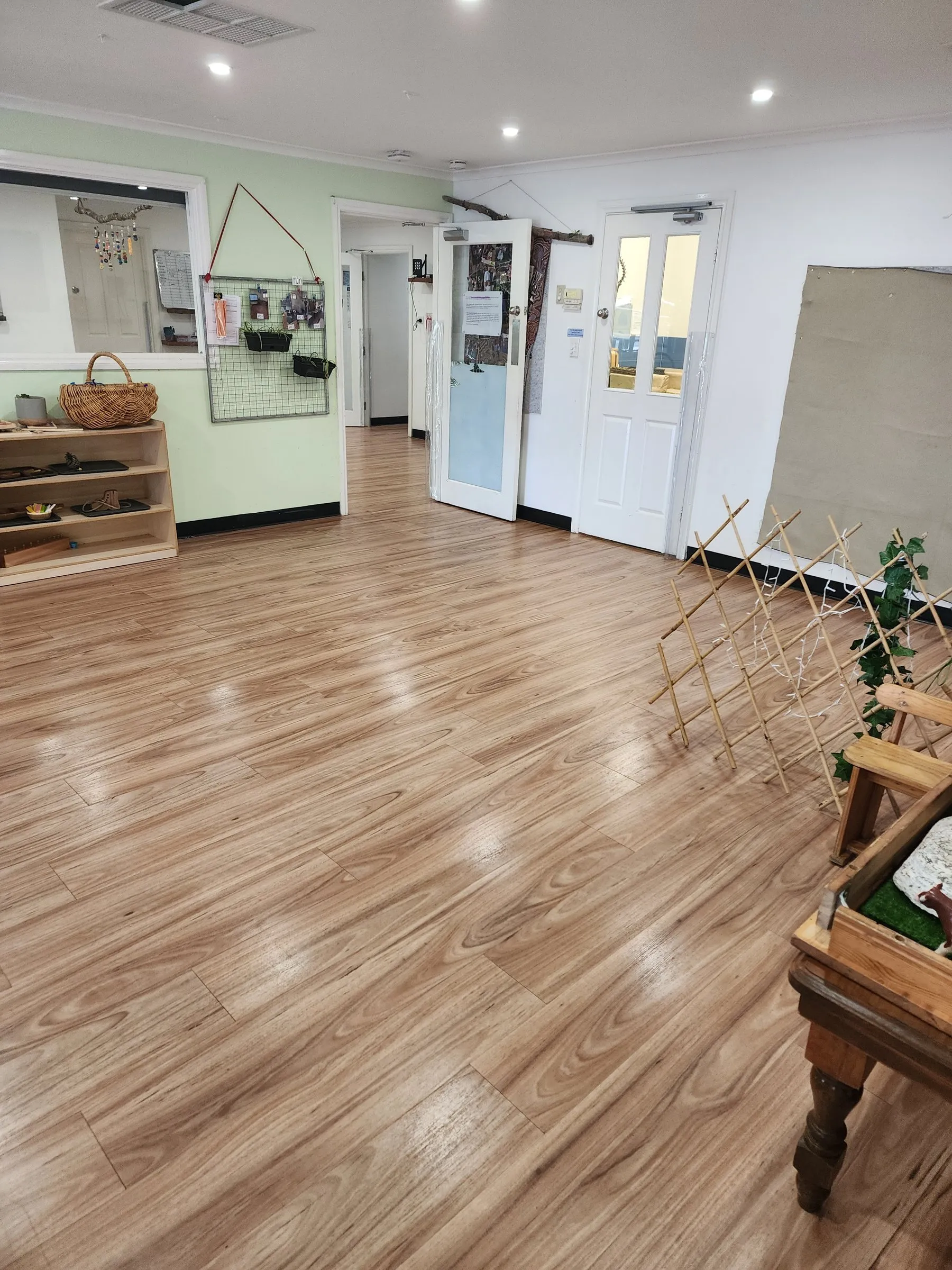 Childcare centre room with a clean timber-look floor and low shelving