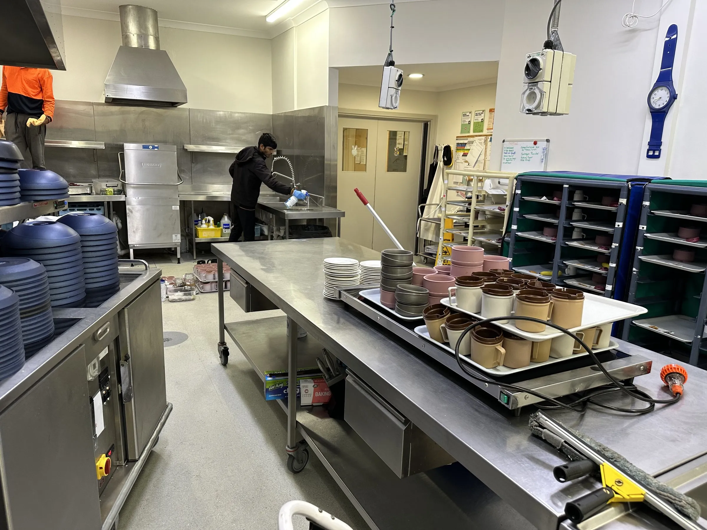 Commercial kitchen during a clean, trays on the stainless bench