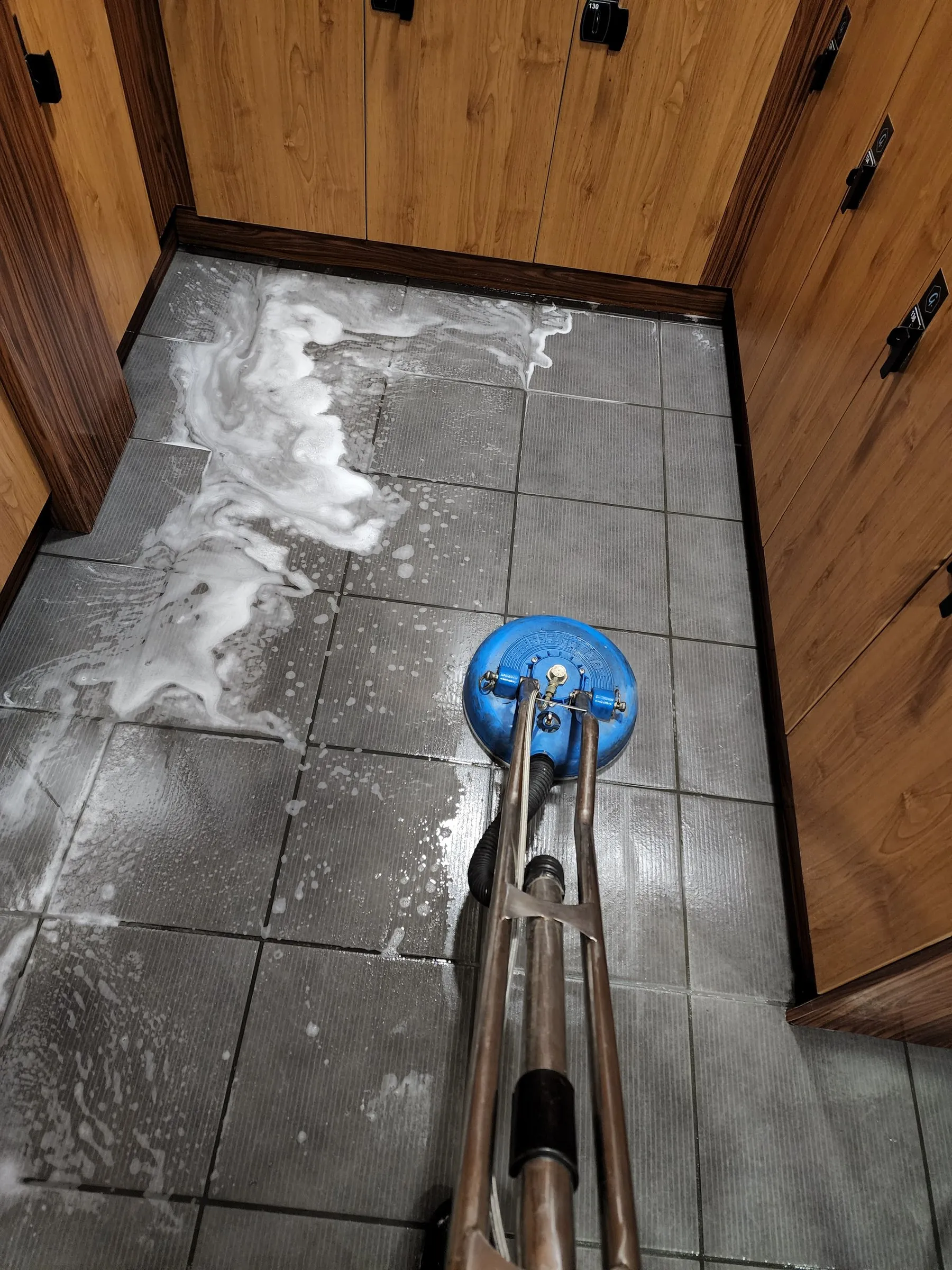 Spinner wand scrubbing change room tiles beside timber lockers